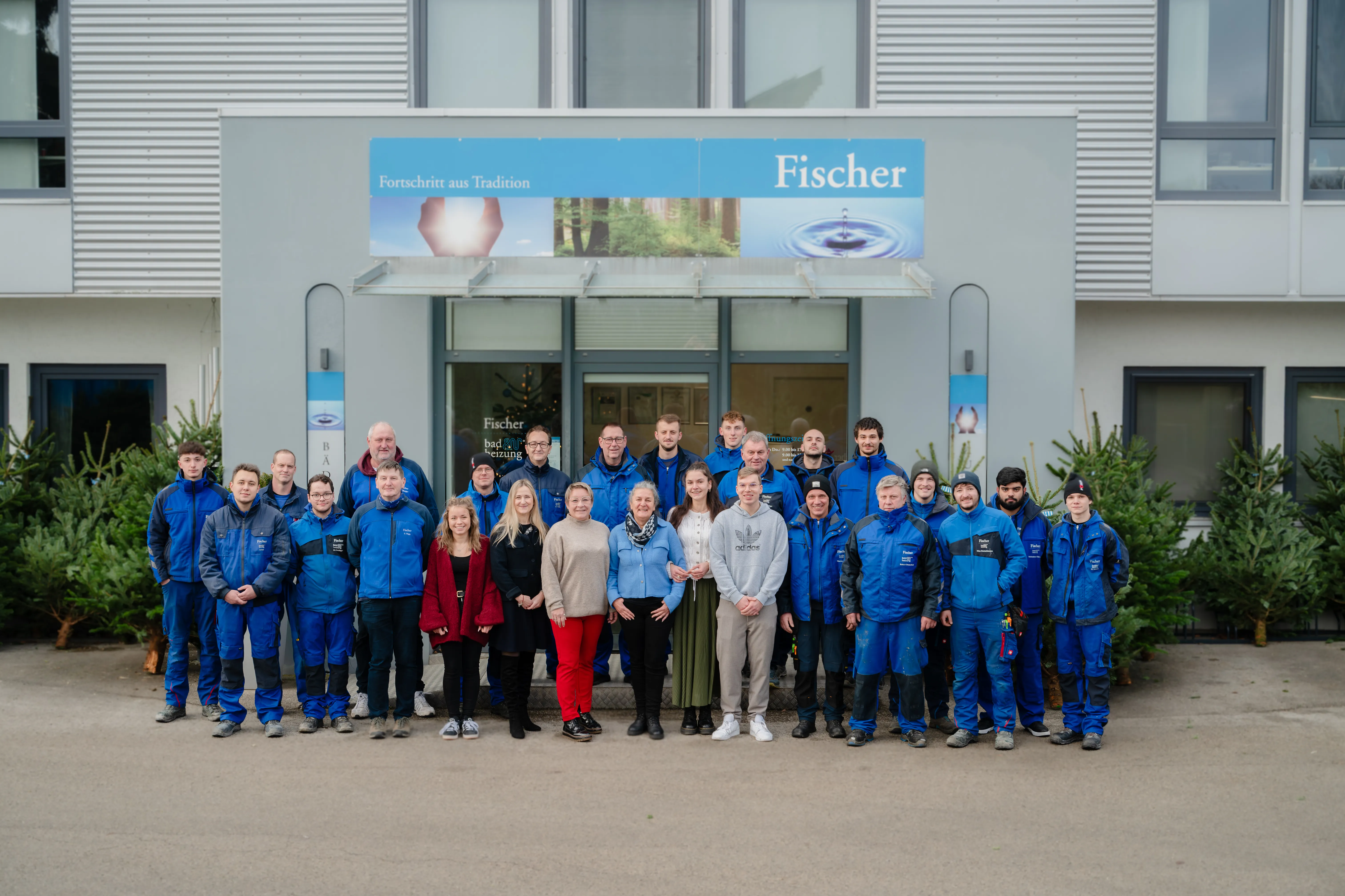 Gruppenfoto des Teams der Fischer GmbH vor dem Gebäude des Unternehmens.