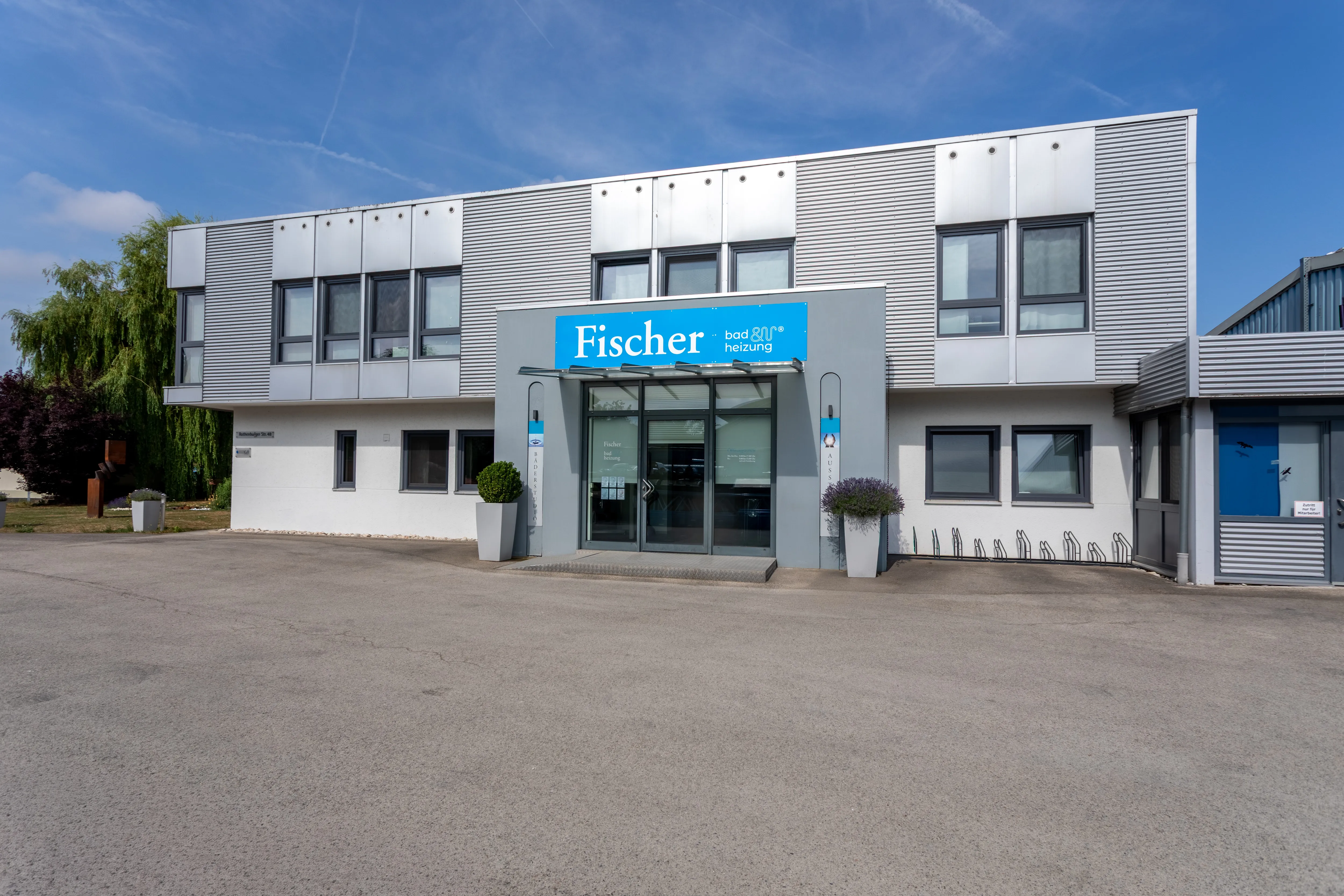 Eingangsbereich des Firmengebäudes von Fischer Bad & Heizung mit modernem Fassadendesign.