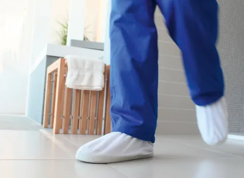 Badmonteur mit schmutzvermeidenden Überziehschuhen.