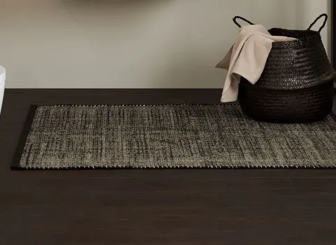 Wohnliches Bad mit wandhängendem Dusch-WC, Holzwaschtisch, Glasabtrennung und schwarzem Korb. Schlichte, moderne Gestaltung.