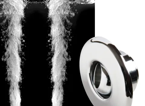 Zwei kraftvolle Wasserstrahlen schießen aus den Rückendüsen einer Whirlwanne, umgeben von sprudelndem Wasser. Rechts im Bild ist eine verchromte Rückendüse abgebildet. Das Bild zeigt die Funktion und das Design der Düsen für ein entspannendes Massageerlebnis.