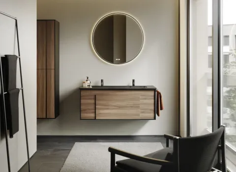 Ein stilvolles Badezimmer zeigt ein Möbelset aus der Serie burgbad Modo mit einem schwebenden Waschtisch in Holzoptik und schwarzer Waschtischplatte
