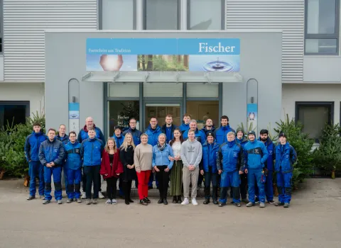 Gruppenfoto des Teams der Fischer GmbH vor dem Gebäude des Unternehmens.