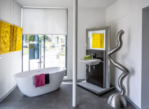 Freistehende Designbadewanne mit modernem Waschplatz in der Badausstellung.