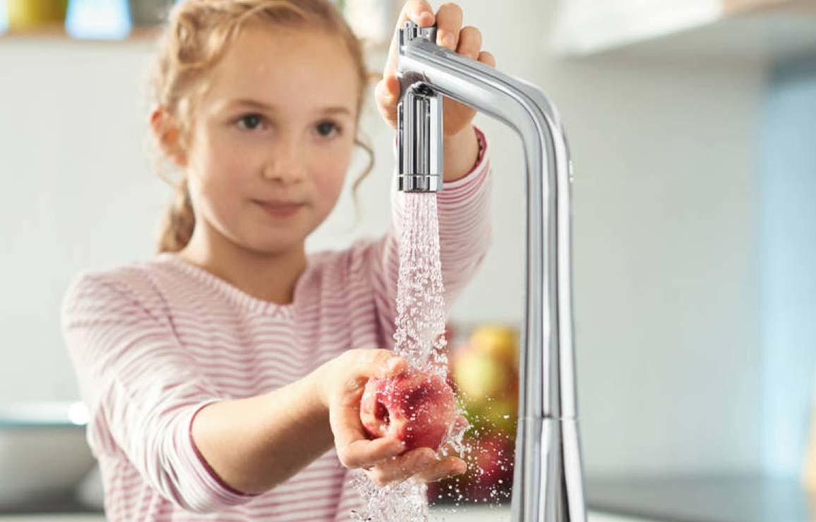 Kind wäscht Obst unter Wasserhahn